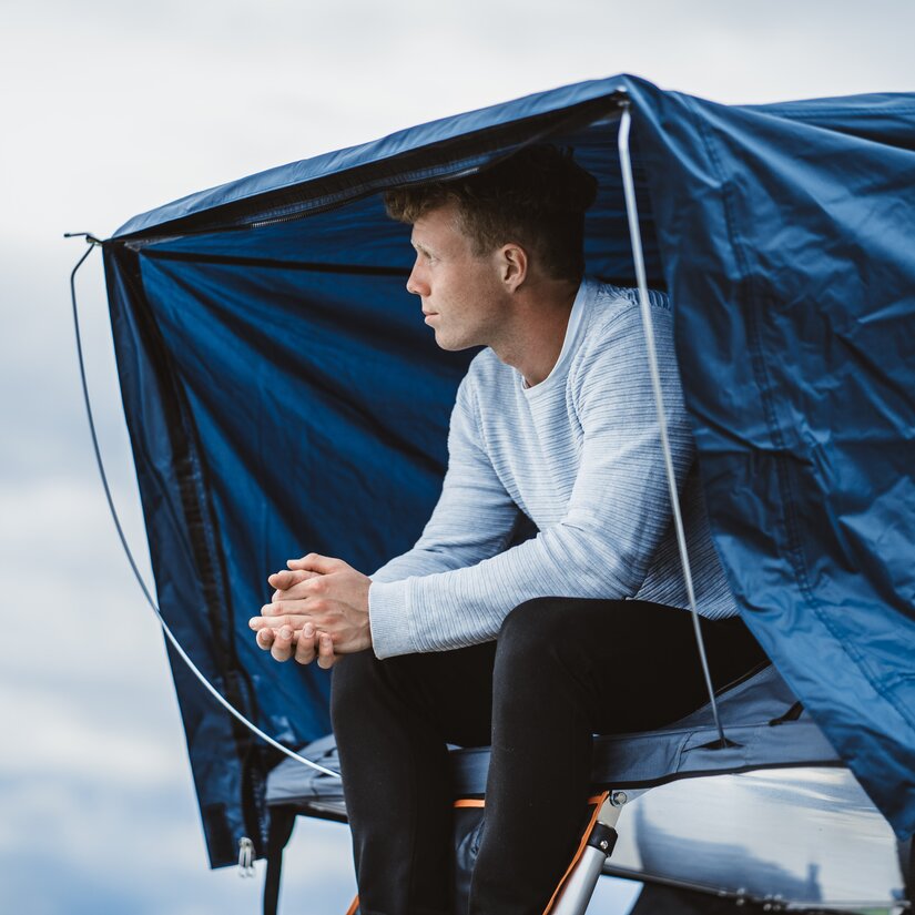 Mand i KINTO Camp telt på toppen af Toyota RAV4 Hybrid med tagtelt